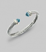 From the Silver Classics Collection. The signature Yurman cable bangle, capped with faceted blue topaz domes and accents of 14k gold. Blue topaz Sterling silver and 14k yellow gold Cable, 7mm Diameter, about 2¼ Imported