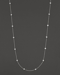 A long white gold chain is spaced with fifteen bezel-set, diamond stations.