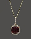 Diamonds frame a faceted garnet, set in 14K yellow gold.