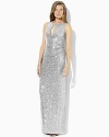 An elegant floor-length gown is rendered in glamorous sequined mesh with a keyhole cutout and graceful slit at the left side seam for added allure.