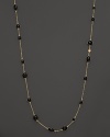 Round and oval black enamel stations and a diamond highlight this gold chain necklace.