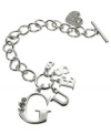 Strike up the brand. This logo and heart bracelet from GUESS is crafted from silver-tone mixed metal, with glass crystals adding a lustrous touch. Item comes packaged in a signature GUESS Gift Box. Approximate length: 7-1/2 inches. Approximate diameter: 1-1/2 inches. Approximate drop: 1 inch.