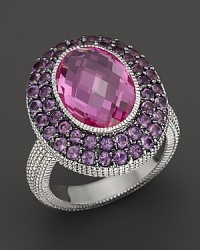 A sterling silver ring with large faceted oval pink corundum stone and wide amethyst pave frame. By Judith Ripka.