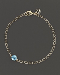 A single faceted blue topaz adds a spot of brilliant color to elegant 18K yellow gold links. By Carelle.