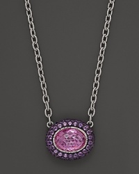 Sterling silver chain necklace adorned with an oval pink corundum pendant with amethyst pave frame. By Judith Ripka.