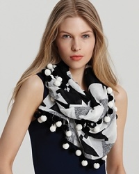 Make a statement with this cozy scarf featuring a black and white abstract check and matching ball trim.