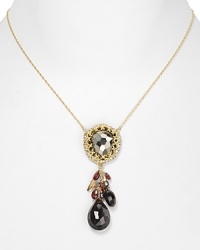 A bold, bejeweled cluster of stones, crystals, and pearls adorns this Alexis Bittar necklace, cast in gold plated metal.